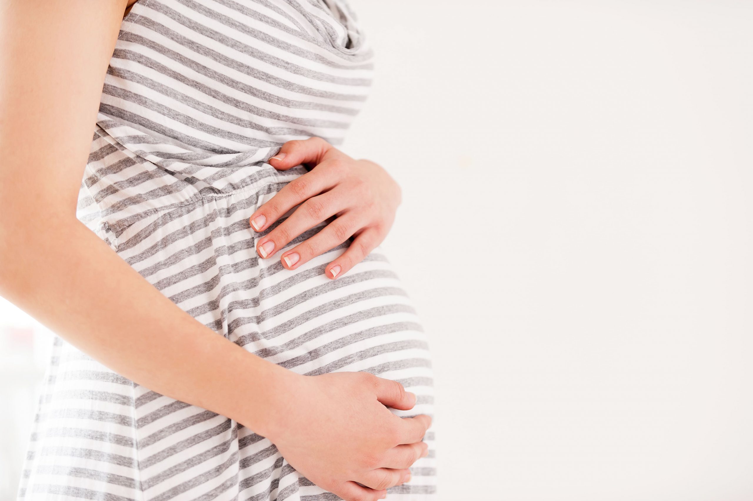 Pregnancy. Side view cropped image of pregnant woman holding hands on her abdomen chiropractor