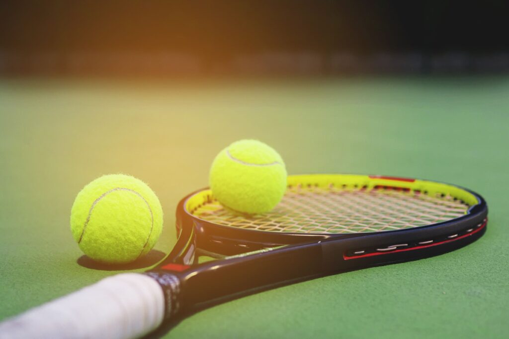 tennis-racket-with-balls-on-court